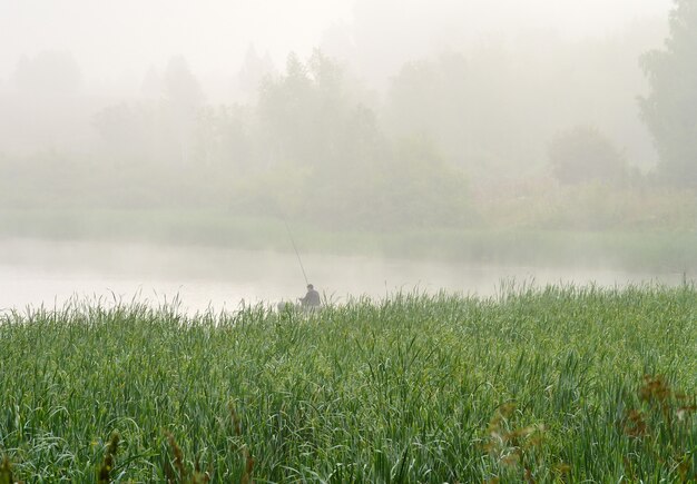 Foto pescador en el lago en la niebla