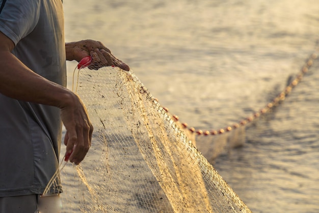 Pescador lançando sua rede ao nascer ou pôr do sol Pescadores tradicionais preparam a rede de pesca