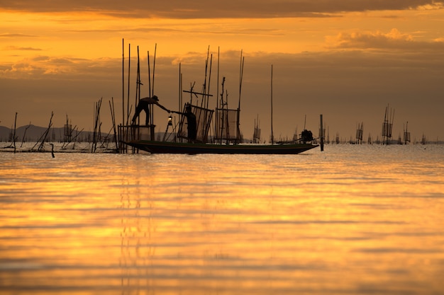 Pescador, ligado, barco, pegando peixe, com, pôr do sol