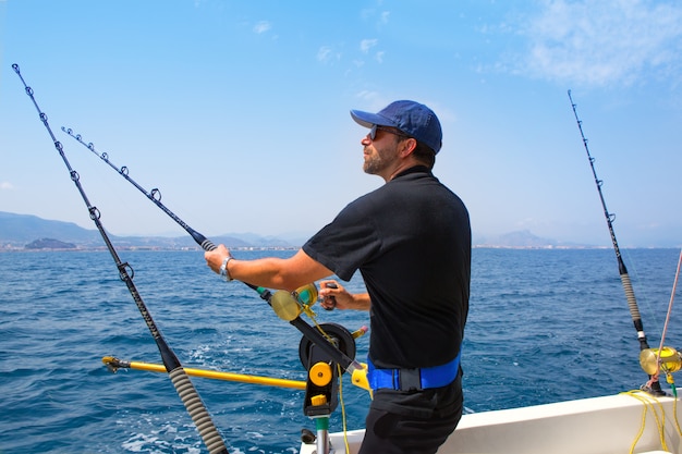 Pescador de mar azul en barco de arrastre con downrigger