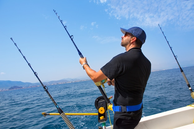 Pescador de mar azul en barco de arrastre con downrigger