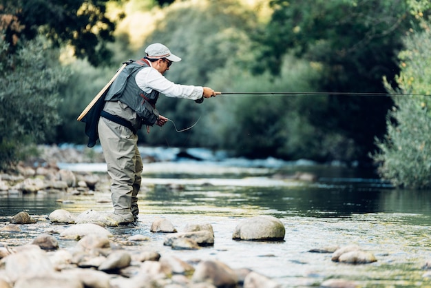 Pescador con mosca con caña de pescar con mosca en río hermoso