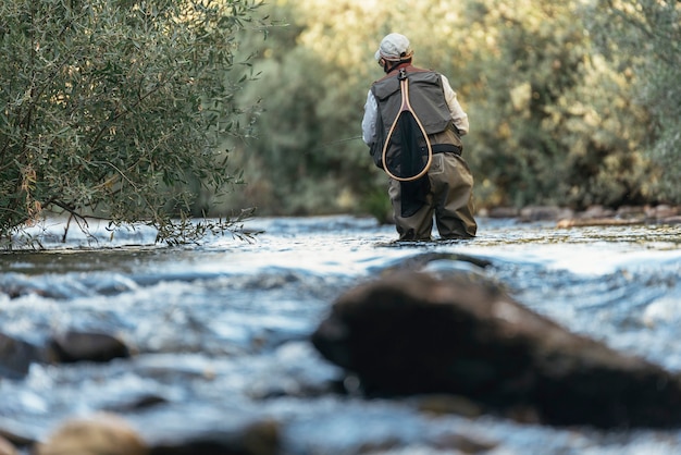 Pescador con mosca con caña de pescar con mosca en río hermoso