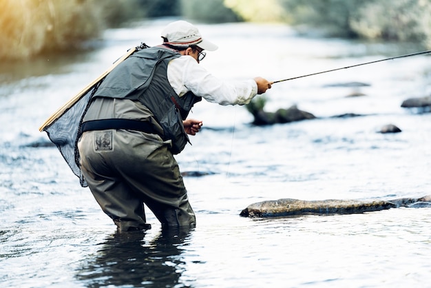 Pescador con mosca con caña de pescar con mosca en río hermoso