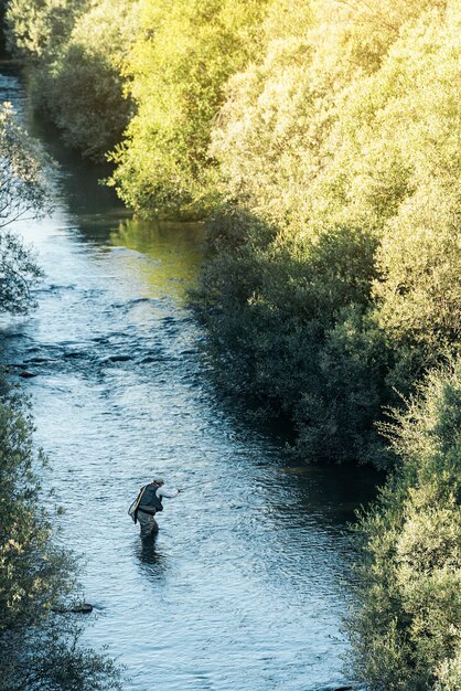 Pescador con mosca con caña de pescar con mosca en río hermoso