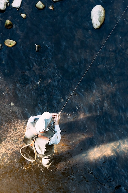 Pescador con mosca con caña de pescar con mosca en río hermoso