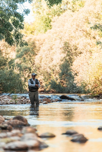 Pescador con mosca con caña de pescar con mosca en río hermoso