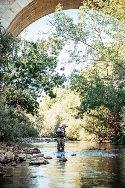 Pescador con mosca con caña de pescar con mosca en río hermoso