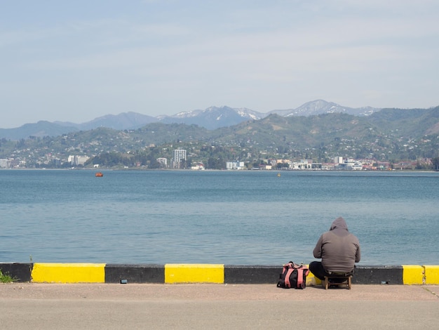 Pescador en el muelle a la orilla del mar Un hombre está sentado en la playa con una caña de pescar