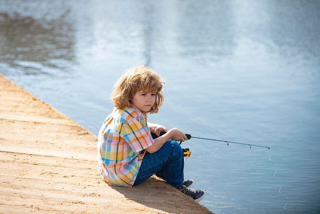 Pescador de niño. Niño pescando en la orilla del río, actividad de ocio al aire libre en verano. Niño pescando con caña en la orilla del río con varilla.