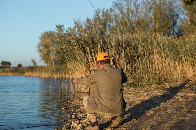 Pescador parado en la orilla del río y tratando de atrapar un pez Estilo de vida deportivo recreativo