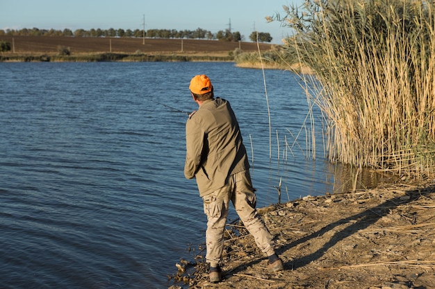 Pescador parado en la orilla del río y tratando de atrapar un pez Estilo de vida deportivo recreativo