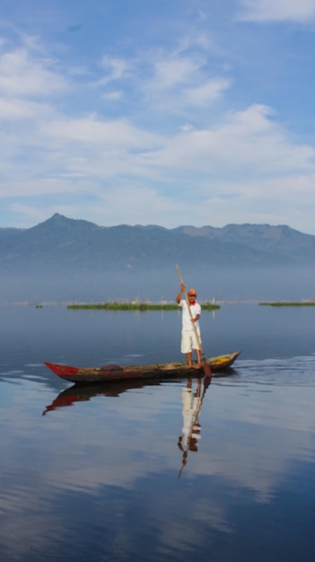 Un pescador pesca con una canoa de madera en Rawa Pening con el monte Merbabu al fondo Canoa de madera