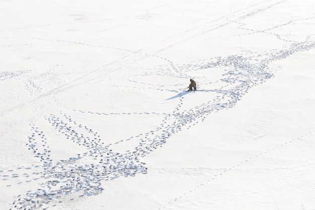 Pescador de pesca de invierno solo en la nieve