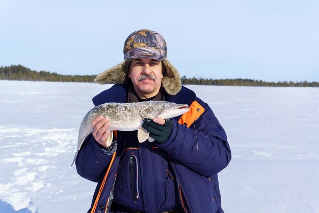 Pescador de pesca de invierno sostiene el trofeo pike Esox lucius espacio para copiar texto