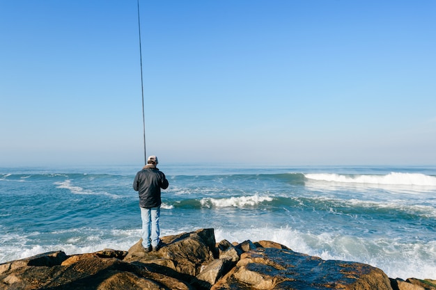 pescador pesca con spinning en el océano