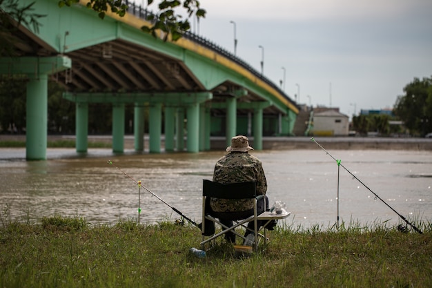 Pescador pescando en la caña de pescar en la orilla del río en el puente