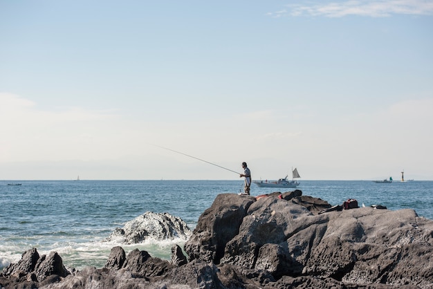 El pescador pescando en la orilla del mar. Paisaje marino japonés