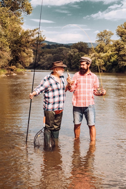 Foto pescador pescando en un río con una caña de pescar feliz abuelo y nieto con cañas de pescar en ...