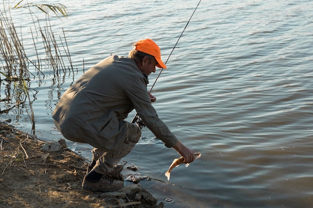 Pescador de pie en la orilla del río y tratando de pescar. Deporte, recreación, estilo de vida.