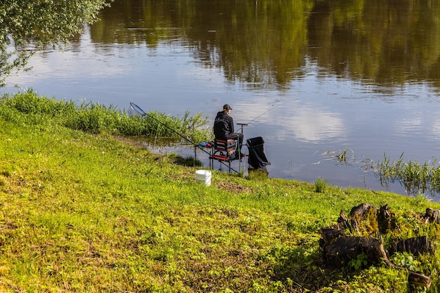 Pescador sentado junto al río en un día soleado