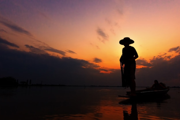 Foto pescador de silueta con puesta de sol