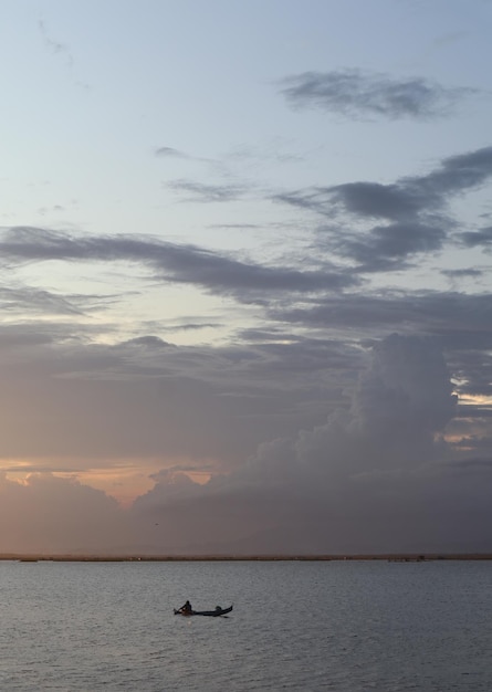 Pescador en su barco al atardecer. Barco de pescadores al atardecer