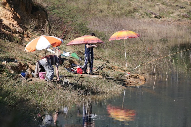 Pescadores à beira da lagoa com uma longa vara de pescar.