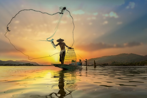 Pescadores asiáticos en barco de pesca en el lago