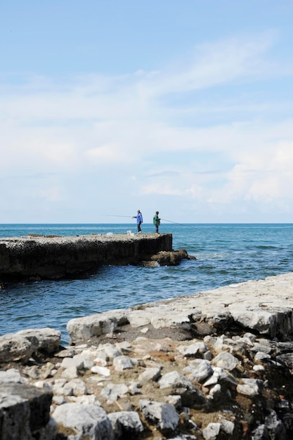 Pescadores com vara de pescar no cais em frente ao mar