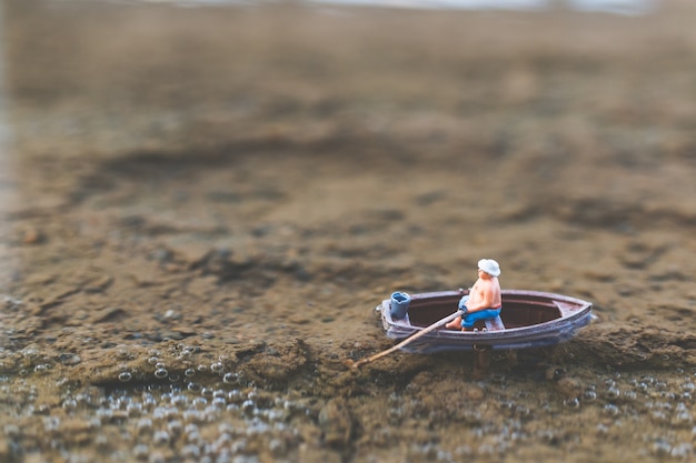 Pescadores em miniatura estão pescando de barco