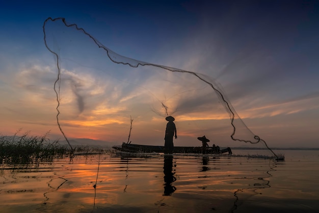 Pescadores lançando estão saindo para pescar no início da manhã com barcos de madeira