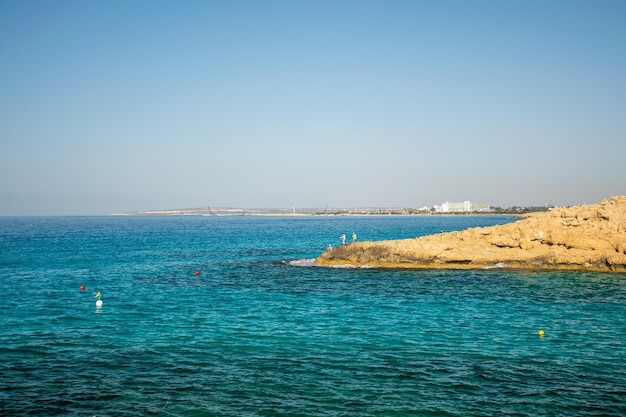 Los pescadores pescan en la costa rocosa del mar azul