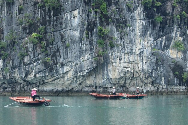 Foto pescadores en sus barcos en la bahía de halong en vietnam