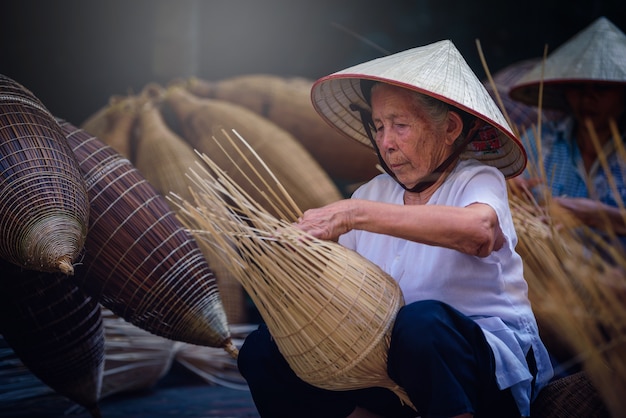 Los pescadores vietnamitas están haciendo cestería para el equipo de pesca en Thu Sy Village