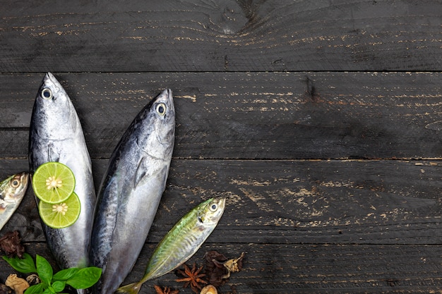 Pescados frescos del atún del barrilete en el fondo de madera negro oscuro