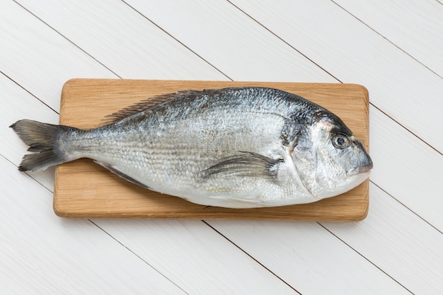 Pescados frescos del dorado en tabla de cortar de madera. Vista superior