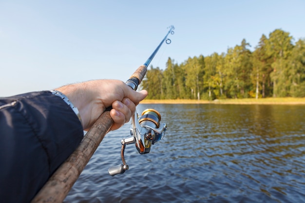 Foto pescando en un lago. caña de pescar con carrete en mano