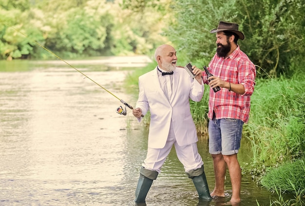 Pescar y beber cerveza Hombres relajantes fondo de naturaleza Diversión y relax Tiempo de fin de semana Hombre barbudo y elegante hombre de negocios pescando juntos Habilidades de pesca Caña de pescar con anzuelo y plomo