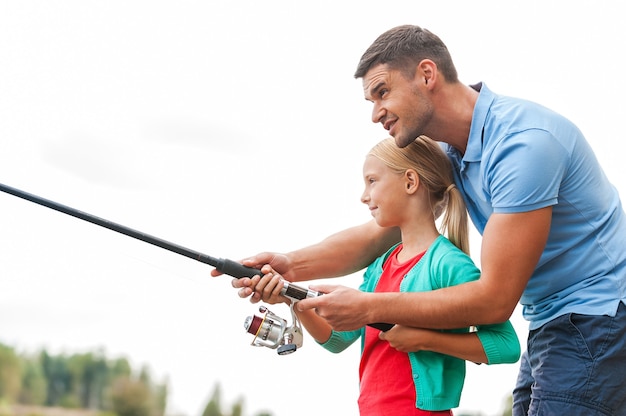 Pescar é divertido. Pai e filha alegres pescando juntos e sorrindo