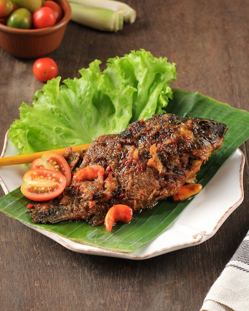 Pesmolfisch mit Goldfisch. Gebratenen Fisch in die Pfanne geben. Pesmol Typisches Fischrezept aus West-Java, Indonesien, mit süßem, saurem und würzigem Geschmack