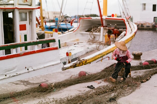 Foto peso completo de un pescador con una red de pesca sentado en un barco