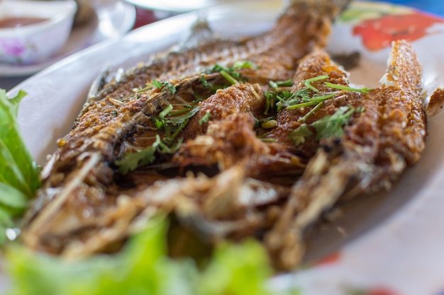 Pesque la salsa de pescados frita en la verdura verde en la tabla de madera