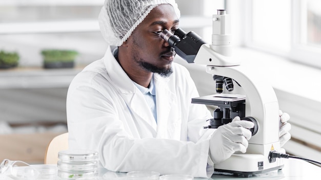 Foto pesquisador masculino no laboratório de biotecnologia com microscópio