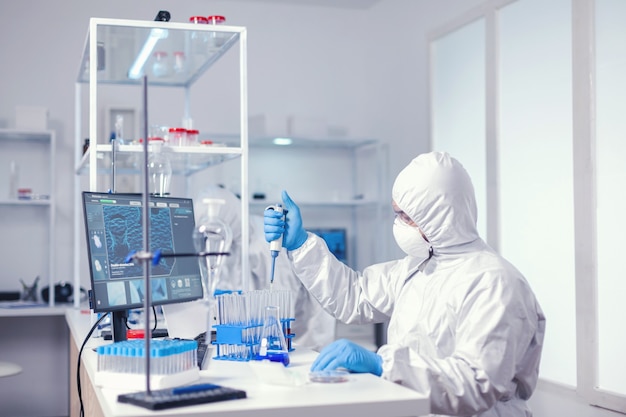 Pesquisador que testa amostra de líquido usa micropipeta em laboratório médico. Químico em um laboratório moderno fazendo pesquisas usando o dispensador durante a epidemia global com covid-19.