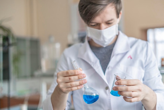 Pesquisador químico trabalha com duas taças com líquido azul b