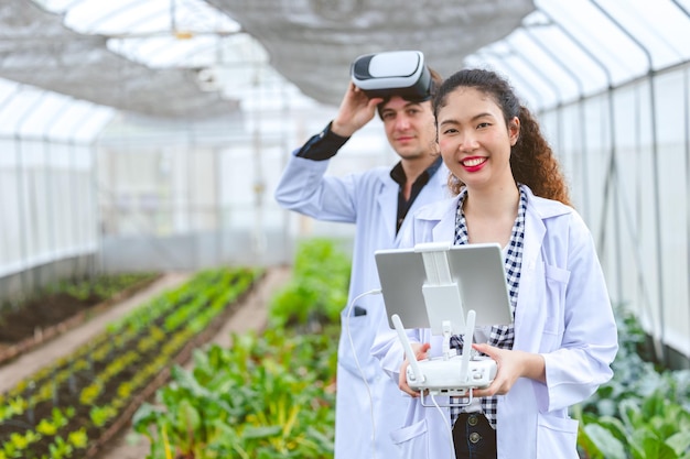 Pesquisador usando controlador de drone com óculos de visão de mosca monitora planta crescendo em fazenda agrícola