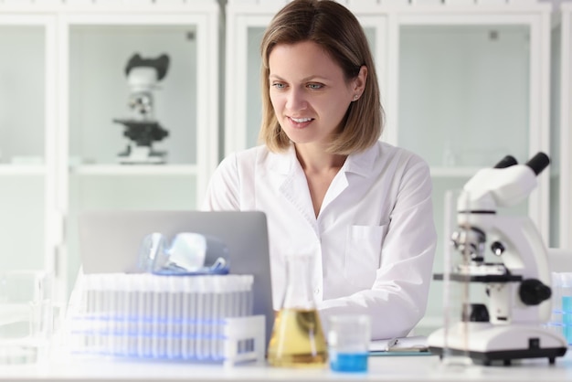 Pesquisadora satisfeita trabalhando no laptop na mesa do laboratório