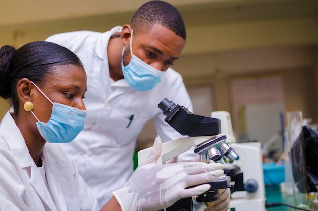 Pesquisadores africanos de saúde trabalhando no laboratório de ciências da vida. jovem cientista de pesquisa e supervisor masculino sênior preparando e analisando lâminas de microscópio no laboratório de pesquisa