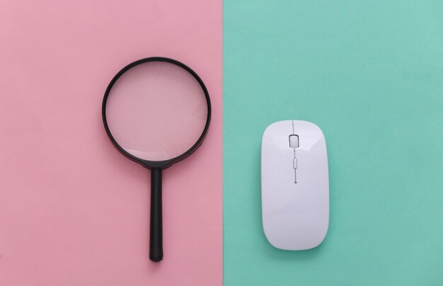 Pesquise informações. Mouse do PC, lupa em fundo rosa azul pastel. Vista do topo